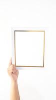 Hand holding empty white colored wooden picture frame isolated on white background photo