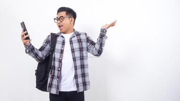 Stressed young Asian male college student with a backpack holding smartphone isolated on white background photo