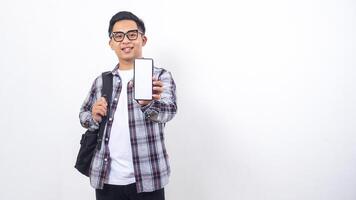Handsome young Asian male college student with a backpack showing blank screen of smartphone mock up isolated on white background photo
