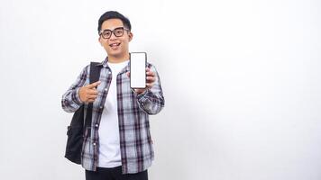 Smiling young Asian male college student with a backpack showing blank screen of smartphone mock up isolated on white background photo