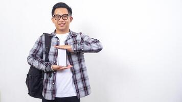 Portrait of smart young Asian male college student with a backpack showing blank screen of smartphone mock up isolated on white background photo