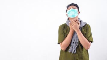 Health issue concept with masked man touching his sore throat isolated on white background photo