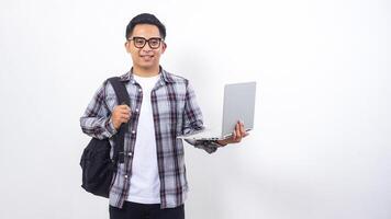 Portrait of smiling young Asian male college student with a backpack and holding open laptop notebook isolated on white background photo
