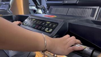 Engaged in a fitness routine, a person grips the handles of a treadmill while navigating the console settings, focused on speed control for an effective cardio workout. video
