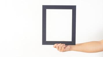 Hand holding empty black colored wooden photo frame isolated on white background