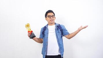 Portrait of smiling young Asian male university student in casual outfit with backpack is holding trophy isolated on white background photo