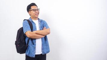 Smiling young Asian male university student in casual outfit with backpack crossing his arms in front of his chest isolated on white background photo