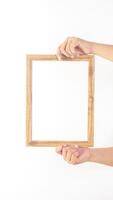 Hand holding empty wooden picture frame isolated on white background photo