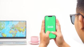 Yogyakarta, Indonesia, 2025 - Man holds smartphone showing Grab, on-demand service platforms in Indonesia application on the screen isolated on white background photo