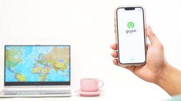 Yogyakarta, Indonesia, 2025 - Man holding smartphone and open Gojek, on-demand service platforms in Indonesia application isolated on white background photo