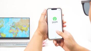 Yogyakarta, Indonesia, 2025 - Man holding smartphone showing Gojek, on-demand service platforms in Indonesia application on the screen isolated on white background photo