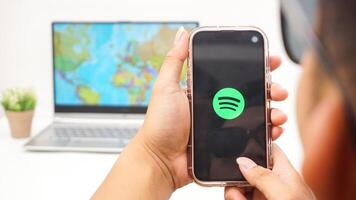 Yogyakarta, Indonesia, 2025 - Man holds smartphone showing Spotify, digital audio streaming platform application on the screen isolated on white background photo