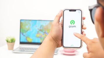 Yogyakarta, Indonesia, 2025 - Man holding smartphone with Gojek, on-demand service platforms in Indonesia application on the screen isolated on white background photo