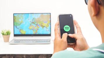 Yogyakarta, Indonesia, 2025 - Man holding smartphone showing Spotify, digital audio streaming platform application on the screen isolated on white background photo