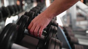 Man picking up dumbbell from rack in gym video
