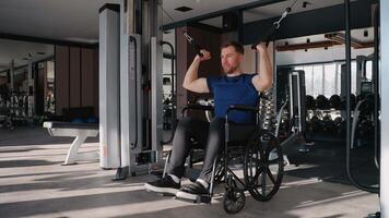 Man in wheelchair using lat pulldown machine in gym video