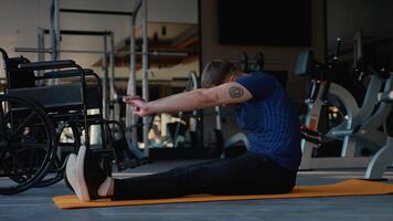 Man with disability doing seated forward stretch on gym mat video