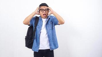 Stressed young Asian male university student in casual outfit with backpack isolated on white background photo