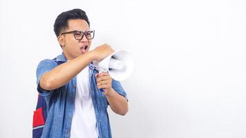 Close up of young Asian male university student in casual outfit with backpack is shouting on megaphone isolated on white background photo