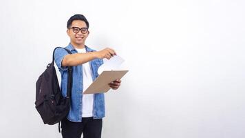 Young Asian male university student in casual outfit with backpack and clipboard isolated on white background photo