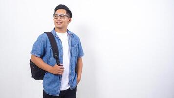 Smiling young Asian male university student in casual outfit with backpack isolated on white background with copy space photo