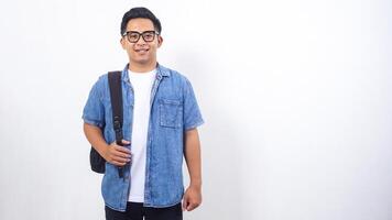 Young Asian male university student in casual outfit with backpack isolated on white background photo