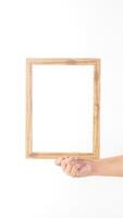 Hand holding empty wooden photo frame isolated on white background