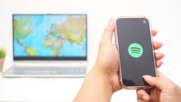Yogyakarta, Indonesia, 2025 - Man holds smartphone with Spotify, digital audio streaming platform application on the screen isolated on white background photo