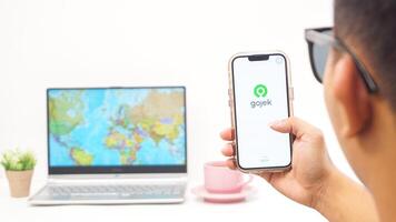 Yogyakarta, Indonesia, 2025 - Man holds smartphone and open Gojek, on-demand service platforms in Indonesia application isolated on white background photo
