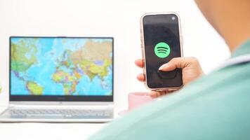 Yogyakarta, Indonesia, 2025 - Man holding smartphone with Spotify, digital audio streaming platform application on the screen isolated on white background photo