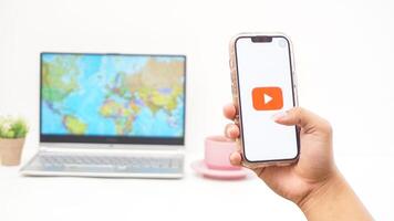 Yogyakarta, Indonesia, 2025 - Man holds smartphone with Youtube platform application is loaded on the screen isolated on white background photo