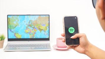 Yogyakarta, Indonesia, 2025 - Man open Spotify, digital audio streaming platform application on the smartphone isolated on white background photo