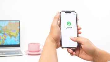 Yogyakarta, Indonesia, 2025 - Man holds smartphone with Gojek, on-demand service platforms in Indonesia application on the screen isolated on white background photo