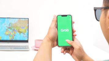 Yogyakarta, Indonesia, 2025 - Man holds smartphone with Grab, on-demand service platforms in Indonesia application is loaded on the screen isolated on white background photo