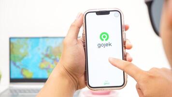 Yogyakarta, Indonesia, 2025 - Man open Gojek, on-demand service platforms in Indonesia application on the smartphone isolated on white background photo