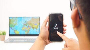 Yogyakarta, Indonesia, 2025 - Man holds smartphone showing Tiktok, social and entertainment platform application on the screen isolated on white background photo