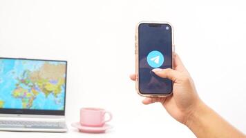 Yogyakarta, Indonesia, 2025 - Man open Telegram, messaging and communication platform application on the smartphone isolated on white background photo