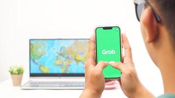 Yogyakarta, Indonesia, 2025 - Man holds smartphone with Grab, on-demand service platforms in Indonesia application on the screen isolated on white background photo