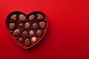 Festive box in the shape of a heart with chocolates on a red background. Top view with place for text for Valentine's day, date and other holiday photo