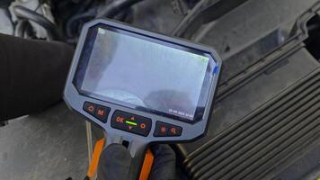 Mechanic inspecting engine with borescope camera, diagnostic tool displays internal engine parts during detailed automotive maintenance procedure in workshop video