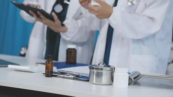 Two doctors are standing at a table with a tablet video