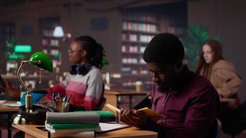 African american guy highlighting essential handwritten class notes to integrate in diploma paper with citations from academic sources within the library database. Research collection. Camera A. video