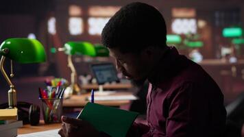 African american guy studies for a critical law exam and reading specialty books to complete class notes with reliable academic information. Studying in the library before the test. Camera A. video