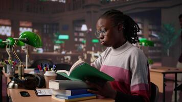 Female pupil struggling to stay focused and awake while researching, writing on her bachelor paper at the library in order to obtain her university diploma. Complete studies. Camera B. video