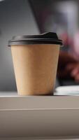 Vertical Male freelancer drinking coffee and solving his daily assignments at home, works on freelancing tasks. Black guy multitasking and answering emails, lifestyle from modern loft. Camera A. video