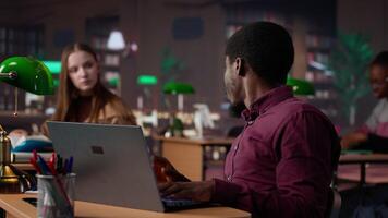 Diverse students working together on a college assignment at the library, consulting the general database and academic collection of specialty books. Young people focus on high grades. Camera A. video