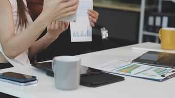 A woman is holding a laptop and a paper with a chart on it video