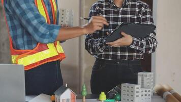 Two men in construction vests and hard hats are working on a project video