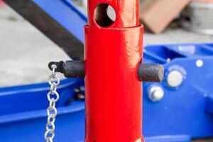 Close-up of the adjustable height locking pin and support column of a red jack stand, used for automotive maintenance and lifting vehicles safely. Car jack stand. photo