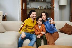 Family enjoying quality time while taking a selfie on a cozy sofa at home photo